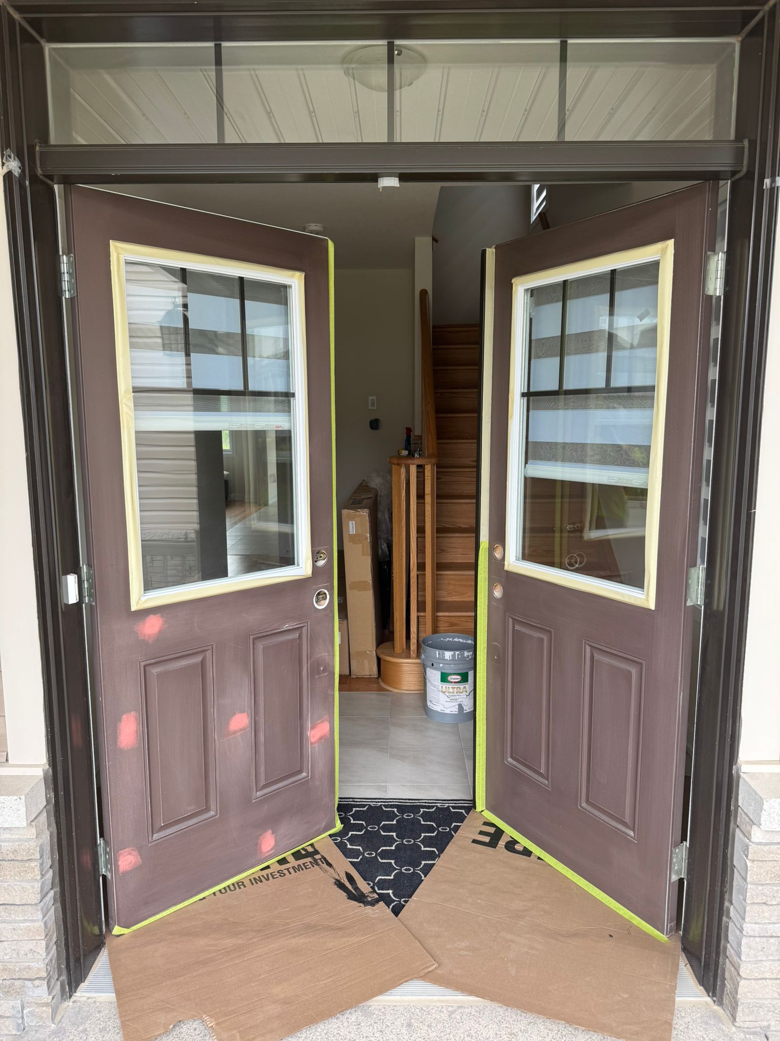 Double front doors masked with tape before painting