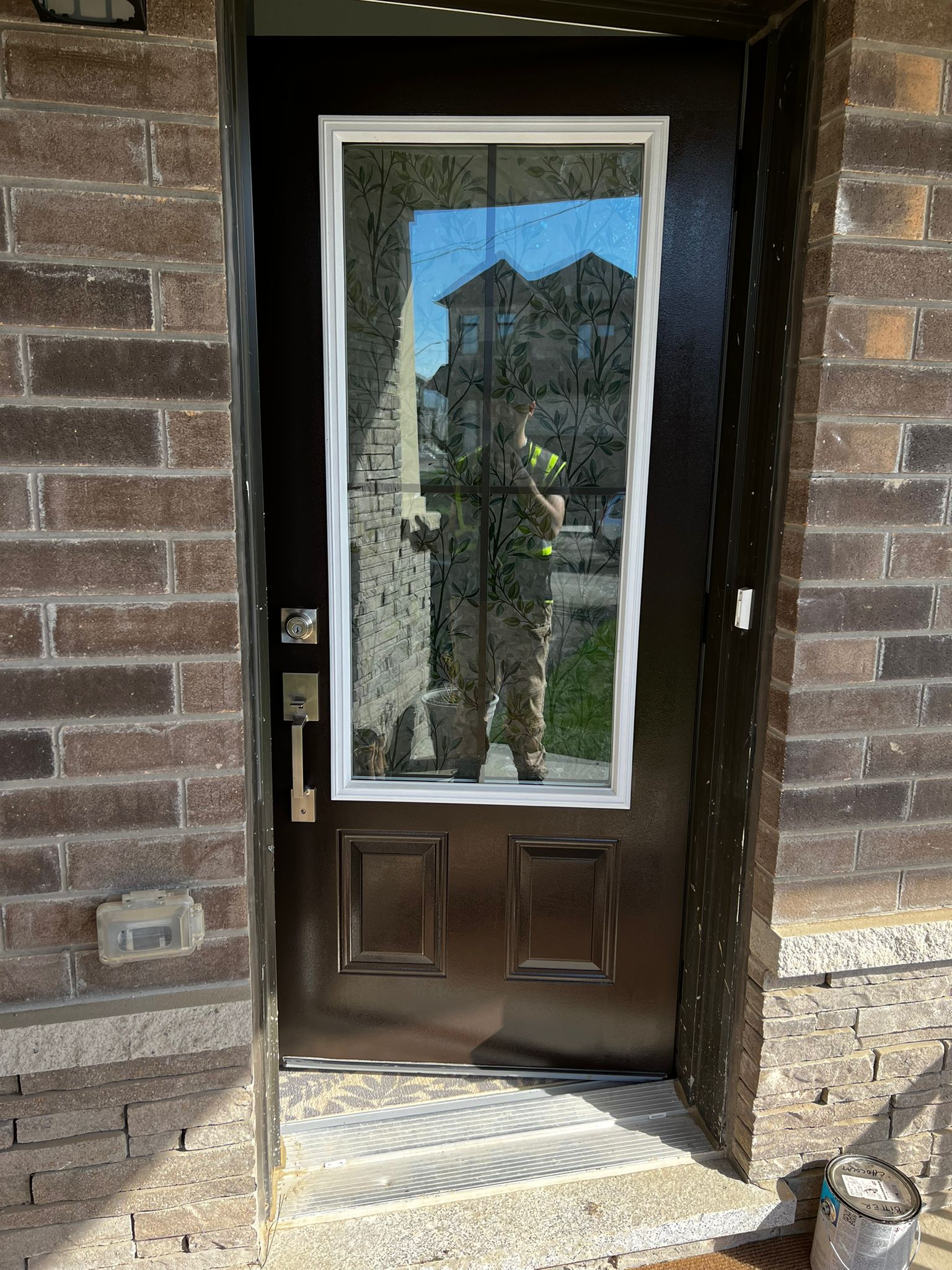 Single front door painted dark brown with decorative glass