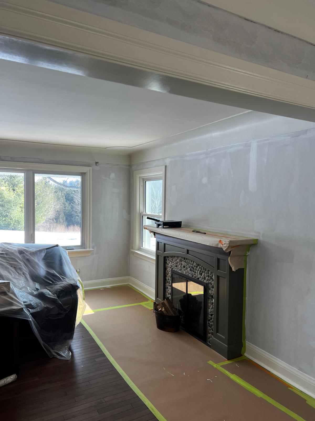 Living room with stone fireplace and walls being primed